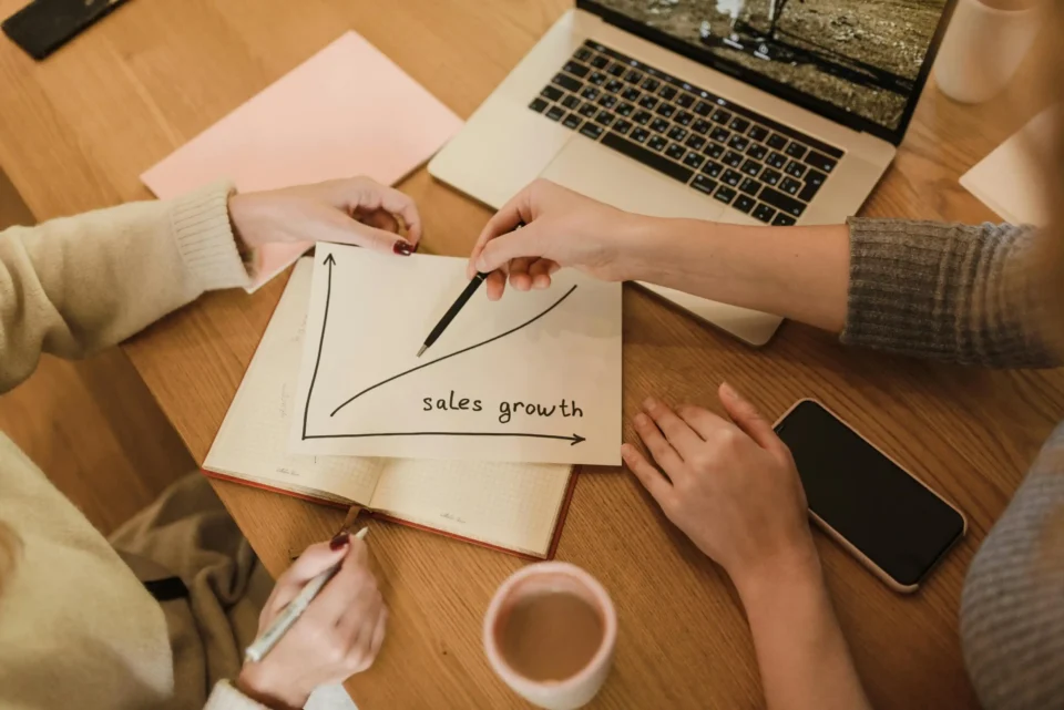 Due persone analizzano un grafico di crescita delle vendite per valutare strategie su come aumentare le vendite con abbinamenti birra e cibo